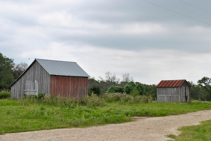 a dirt road next to two old wooden houses