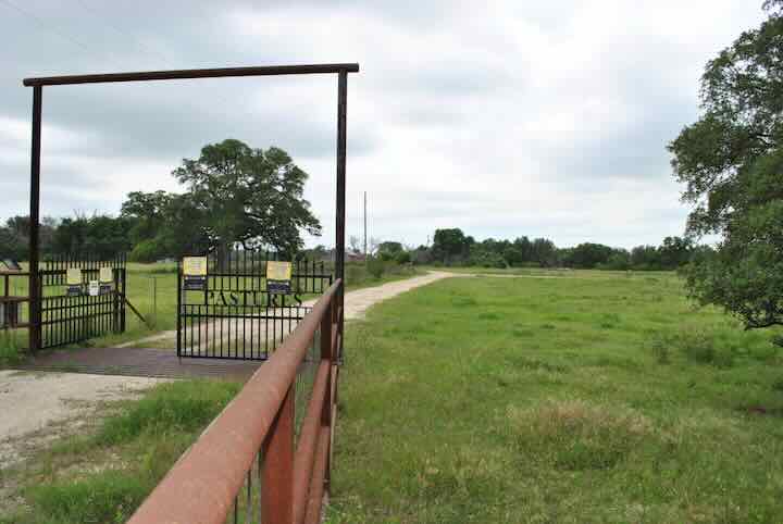 gated in area with a dirt path leading to a grassy field